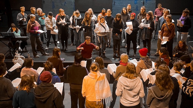 Viele Menschen stehen in einem Raum und singen zusammen.