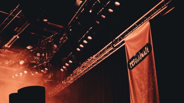 Ein Banner hängt an einem Gerüst in einer Halle.