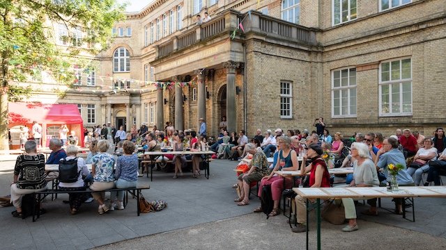Menschen sitzen auf Bänken vor der Hochschule für Künste in Bremen.