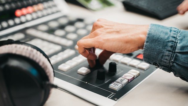 Eine Hand bedient Knöpfe in einem Studio.